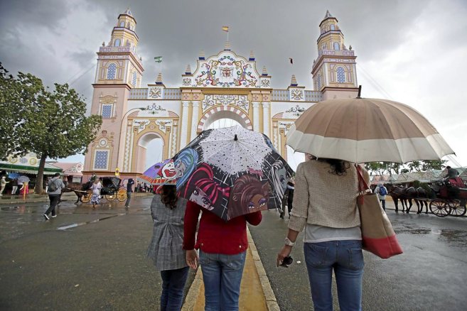 Un grupo de personas se resguarda de la lluvia bajo sus paraguas ante...