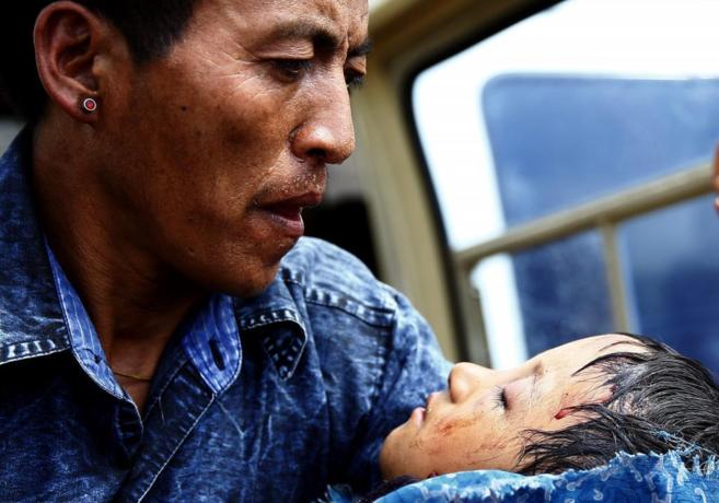 Un padre sostiene a su hijo herido mientras son evacuados a Katmandú.