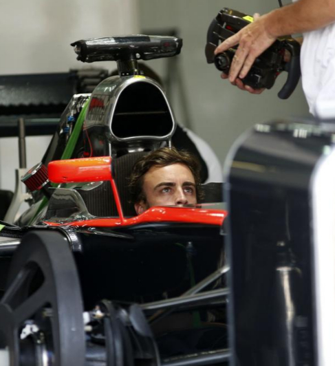 Fernando Alonso observa una pantalla en el box de McLaren.