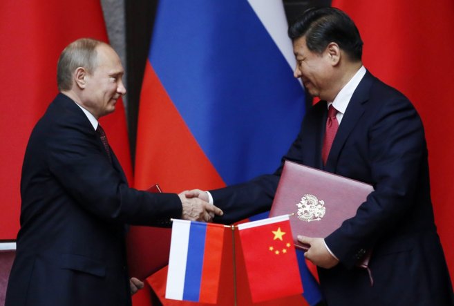 Vladimir Putin y Xi Jinping se dan la mano tras firmar un acuerdo...