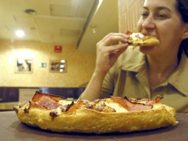 Una joven como pizza en una pizzería.