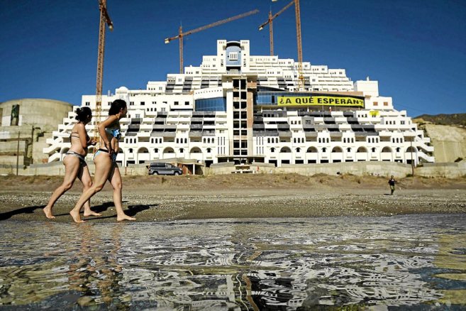 Dos baistas pasean por las proximidades del hotel, en la playa de El...