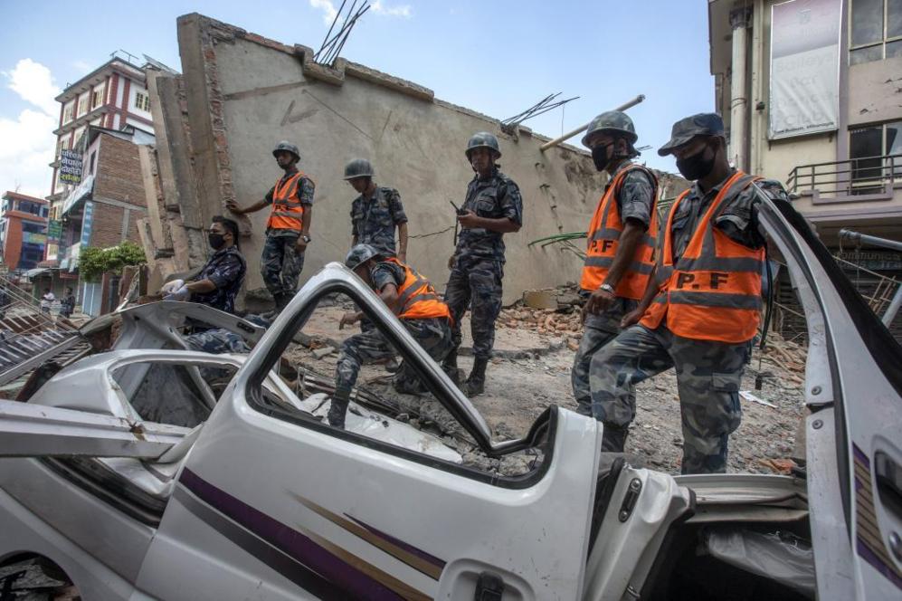 Miembros del Ejrcito permanecen de pie sobre un edificio colapsado...