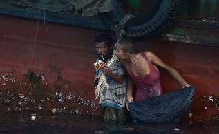 Un inmigrante come vveres colgado de un barco. AFP