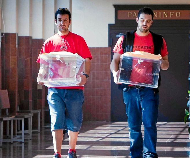 Dos jóvenes trasladan dos urnas en las pasadas elecciones