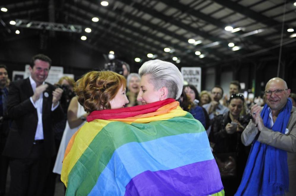 Dos mujeres celebran el resultado envueltas en la bandera arcoiris.