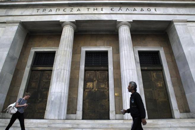 Dos personas pasan junto al Banco central griego en Atenas.