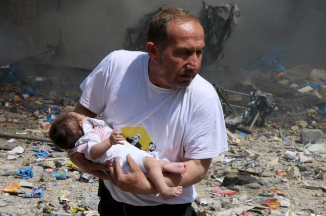 Un hombre sostiene a un beb que sobrevivi a un bombardeo en Alepo.