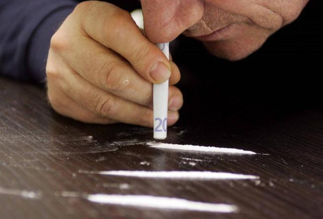 Un hombre esnifa cocaína con un billete de 20 euros.