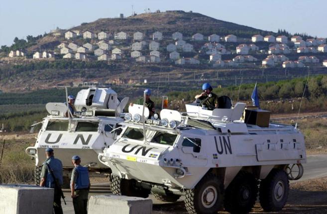 Dos tanquetas de la ONU con varios cascos azules en la frontera de...