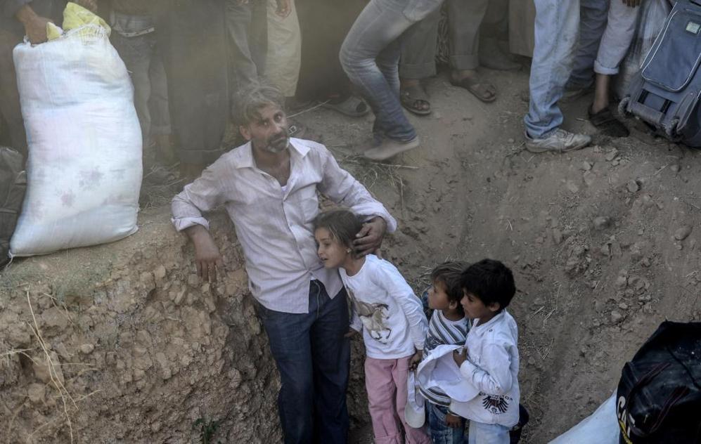 Un hombre sirio aguarda con sus hijos cerca de la frontera con...