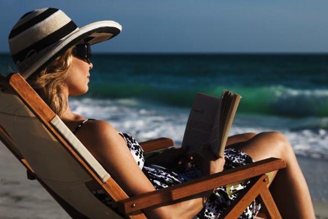 Una mujer lee un libro en la playa.