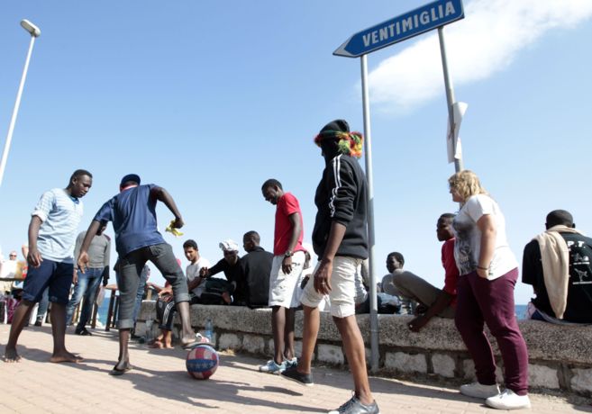 Unos migrantes juegan al fútbol mientras esperan para cruzar a...
