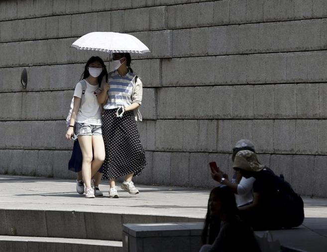 Varias personas pasean con mascarillas por las calles de Seúl.