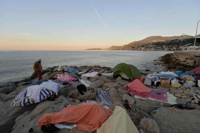 Varios inmigrantes duermen entre rocas a lo largo de la costa de la...
