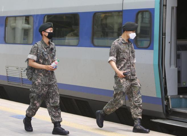 Dos soldados con mascarillas viajan en tren en Sel.