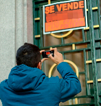 Un joven fotografa un cartel que anuncia la venta de un piso.