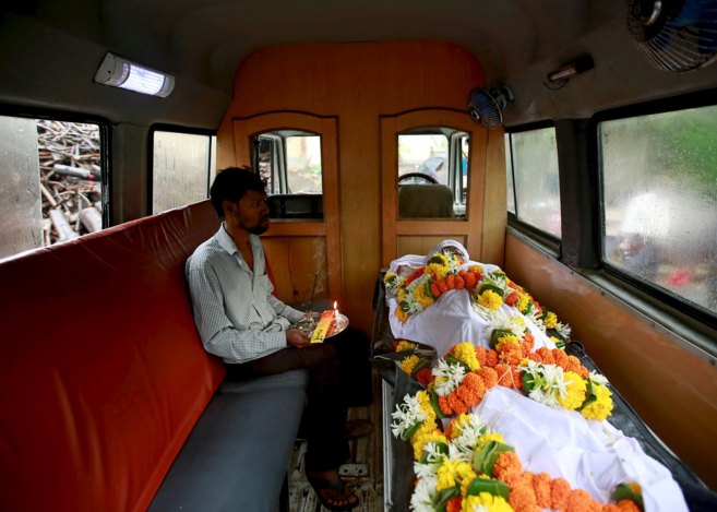 Un indio, junto al cuerpo de una de las víctimas, en una ambulancia,...
