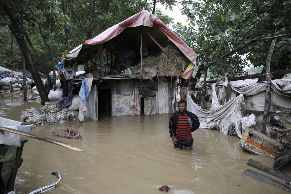 Un chatarrero frente a una casa inundada en un barrio chabolista en...