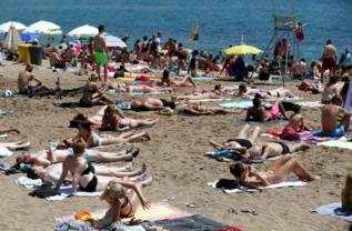 Gente tomando el sol en la playa de la Barceloneta.