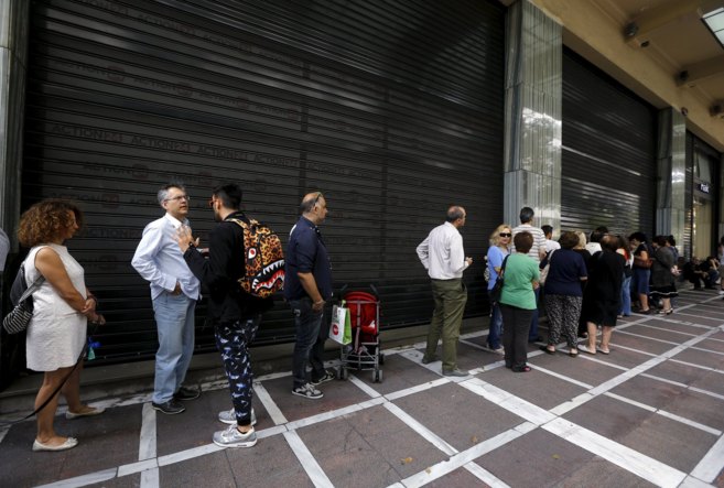 Varios ciudadanos hacen cola ante la entrada de un banco en Atenas.