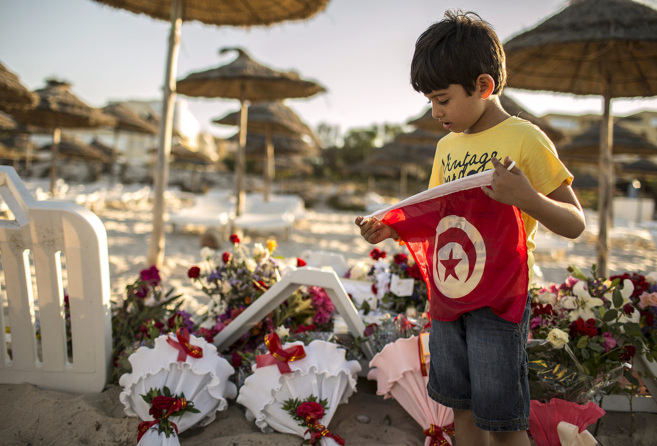 Un nio sostiene la bandera tunecina junto a un altar improvisado por...