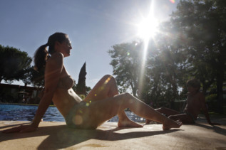Una joven toma el sol junto a una piscina.