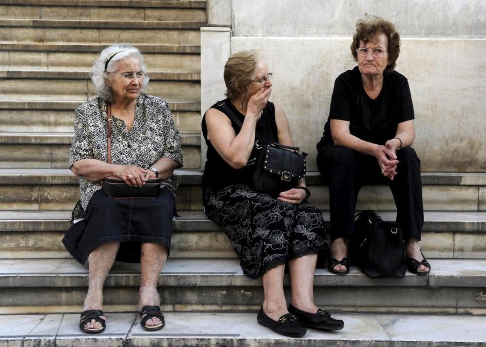 Tres mujeres esperan en la escalinata de una sucursal del Banco...