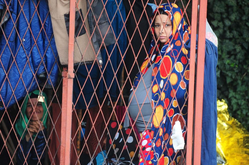 Varios inmigrantes se refugian de la lluvia en una estacin de tren...