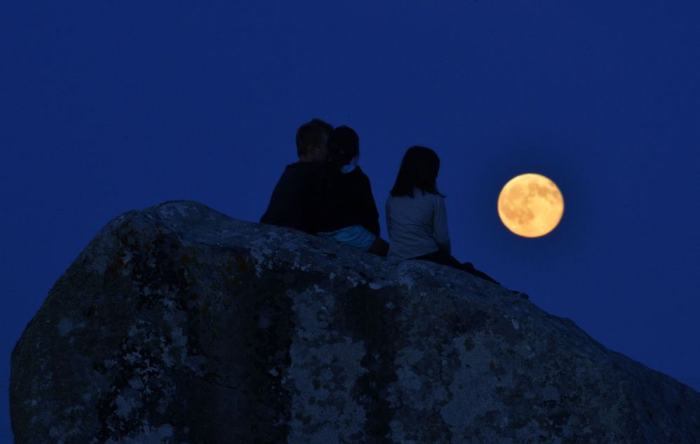 Varios nios observan la luna llena en la Bretaa francesa.