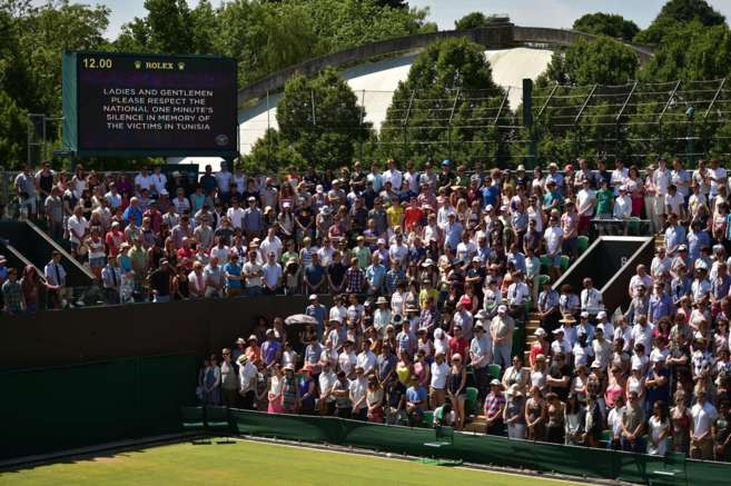 Espectadores del torneo de Wimbledon se paran por el minuto de...