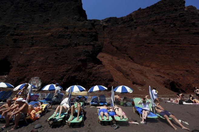 Turistas toman en la Playa Roja de la isla griega de Santorini.