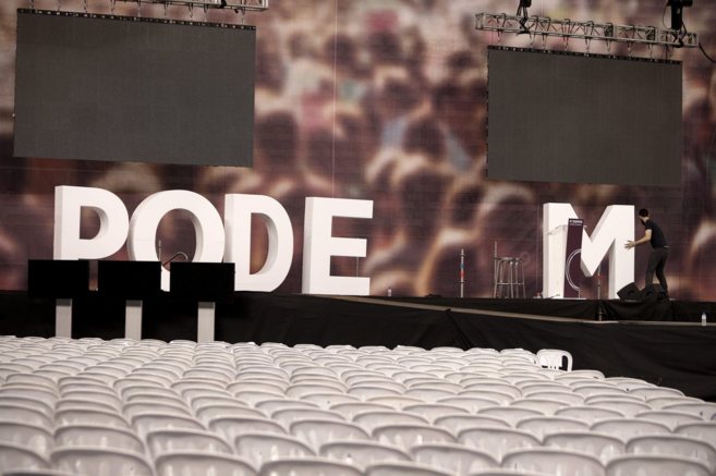 Un operario retira las letras de Podemos que decoraban el escenario de...
