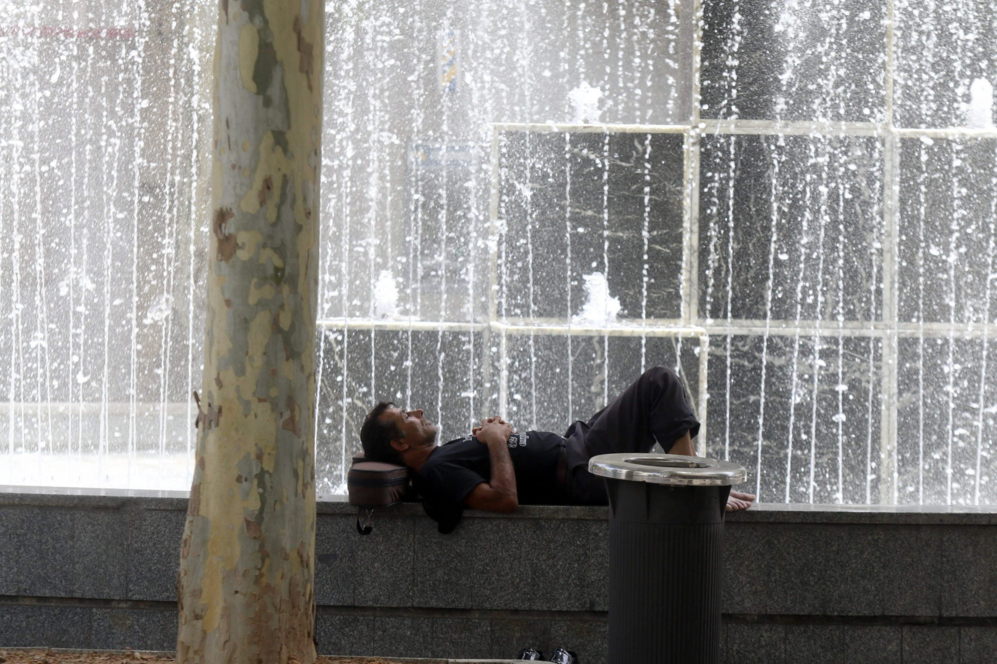Un hombre descansa junto a una fuente de Crdoba.