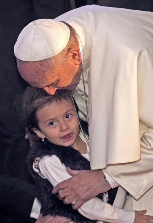 El Papa besa a una nia antes de la misa.