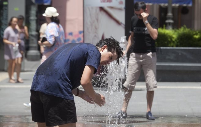 Un joven se refresca en la fuente de una plaza de Córdoba ante las...