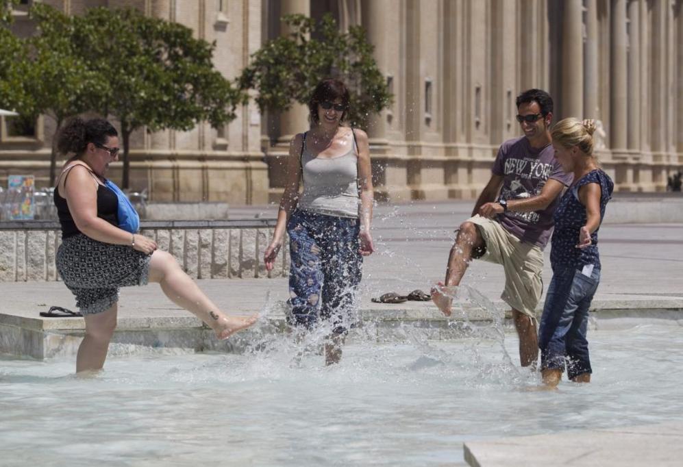 Unos turistas se refrescan en una de las fuentes de la Plaza del Pilar...