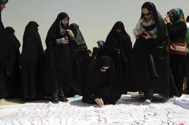 Una iran firma una pancarta durante una ceremonia para apoyar a...