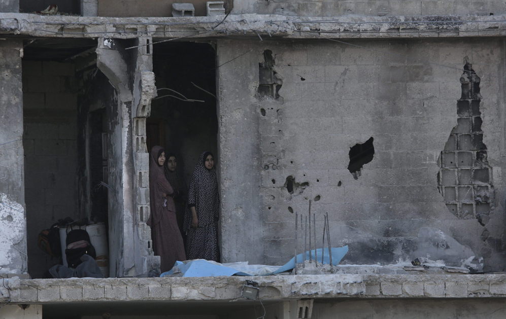 Tres mujeres palestinas conversan en una casa en ruinas del vecindario...