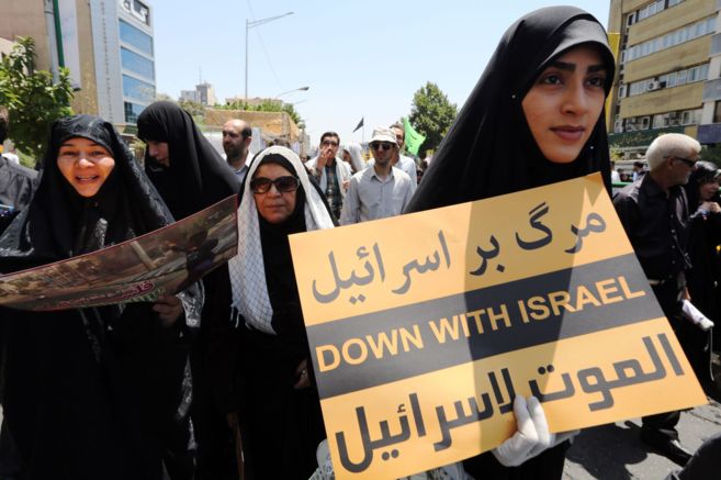Una mujer iran sostiene una pancarta en la que se lee 'Abajo...