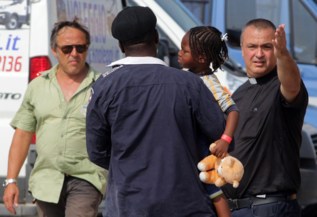 Un inmigrante, con su hija en brazos, llega al puerto de Palermo.