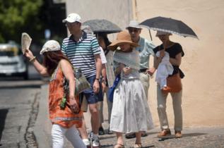 Turistas refugindose bajo parasoles.