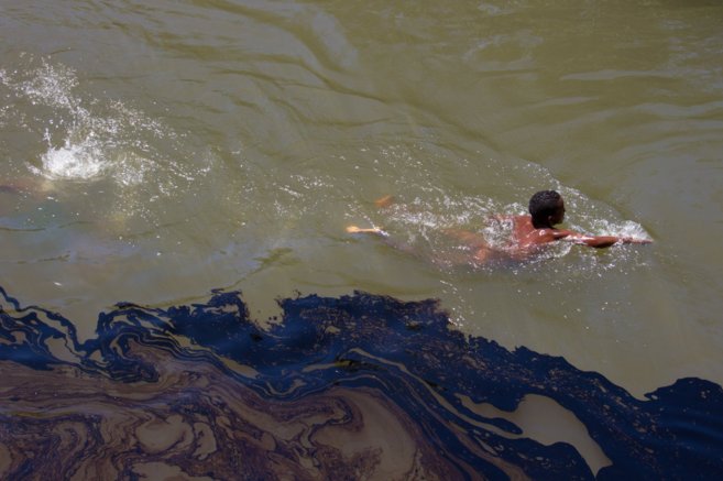 Un nio intenta nadar entre un mar de petrleo derramado por los...