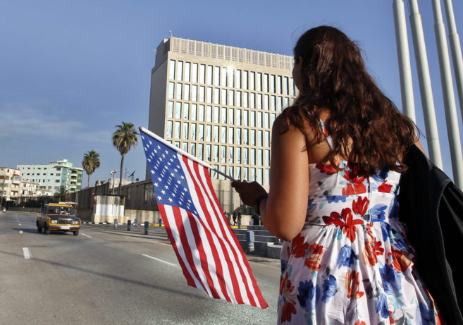 Una mujer camina con una bandera de EEUU frente a la embajada de ese...