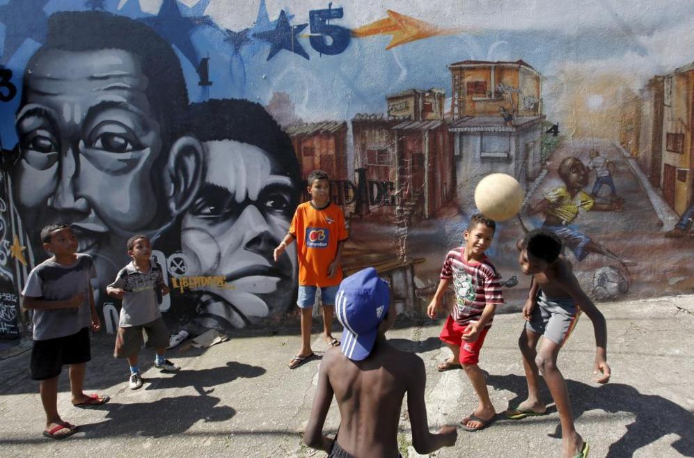 Nios juegan al ftbol ante un graffiti en la favela Vila Flavia de...