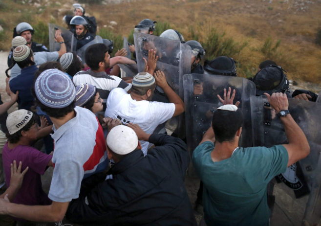 Agentes de seguridad israeles forcejean con colonos israeles en el...