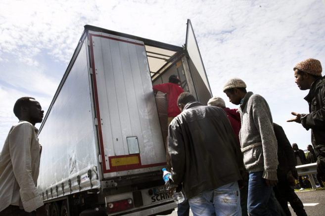 Inmigrantes suben a un camión para acceder al Eurotúnel en Calais en...