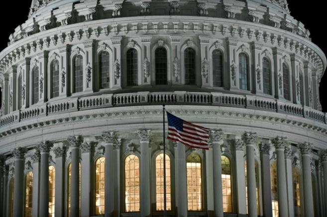 Imagen nocturna del Capitolio, con la bandera de EEUU ondeando.