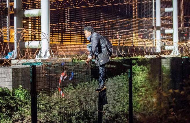 Un inmigrante intenta saltar una valla en Coquelles, cerca de Calais.
