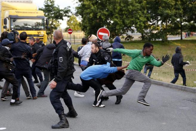 Inmigrantes escapan de las autoridades francesas antes de intentar...